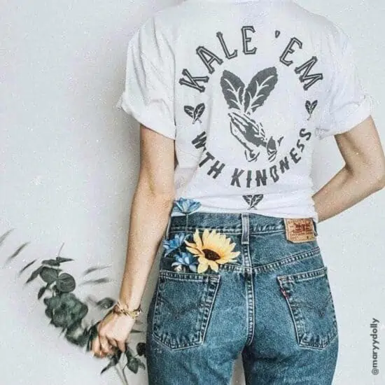 girl wearing white kale em with kindness vegan shirt with sunflower in her back pocket