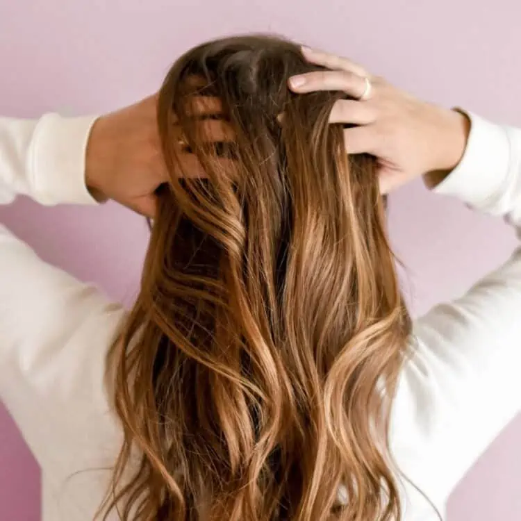 girls with hands in her brown wavy hair loss