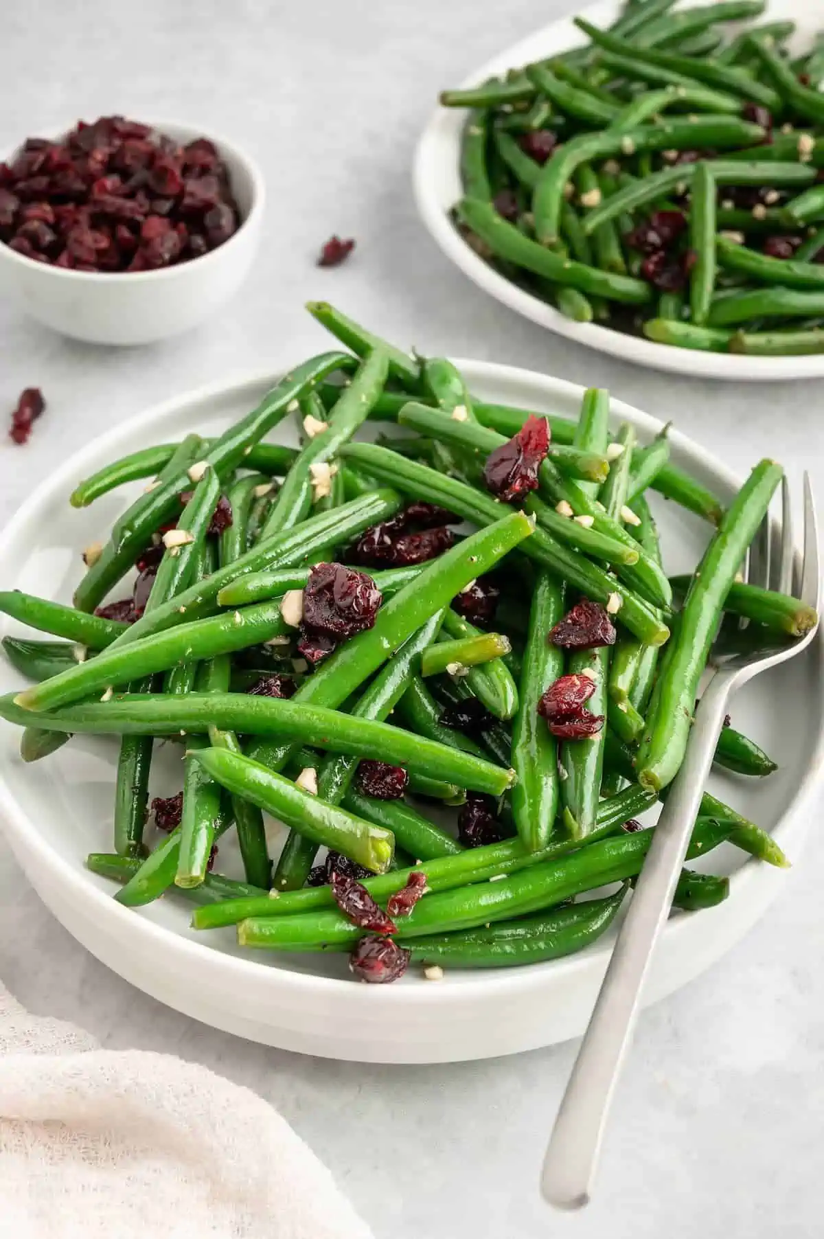 A plate of garlic green beans on a white plate with a fork.