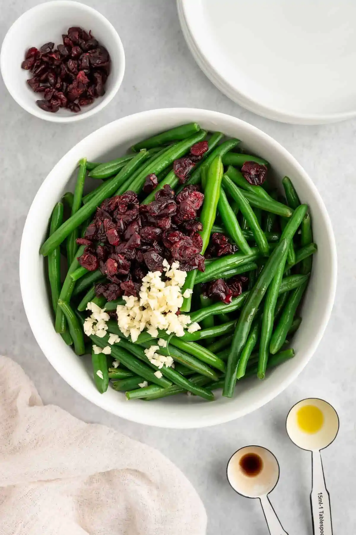 A bowl of green beans with cranberries, minced garlic, and seasonings.