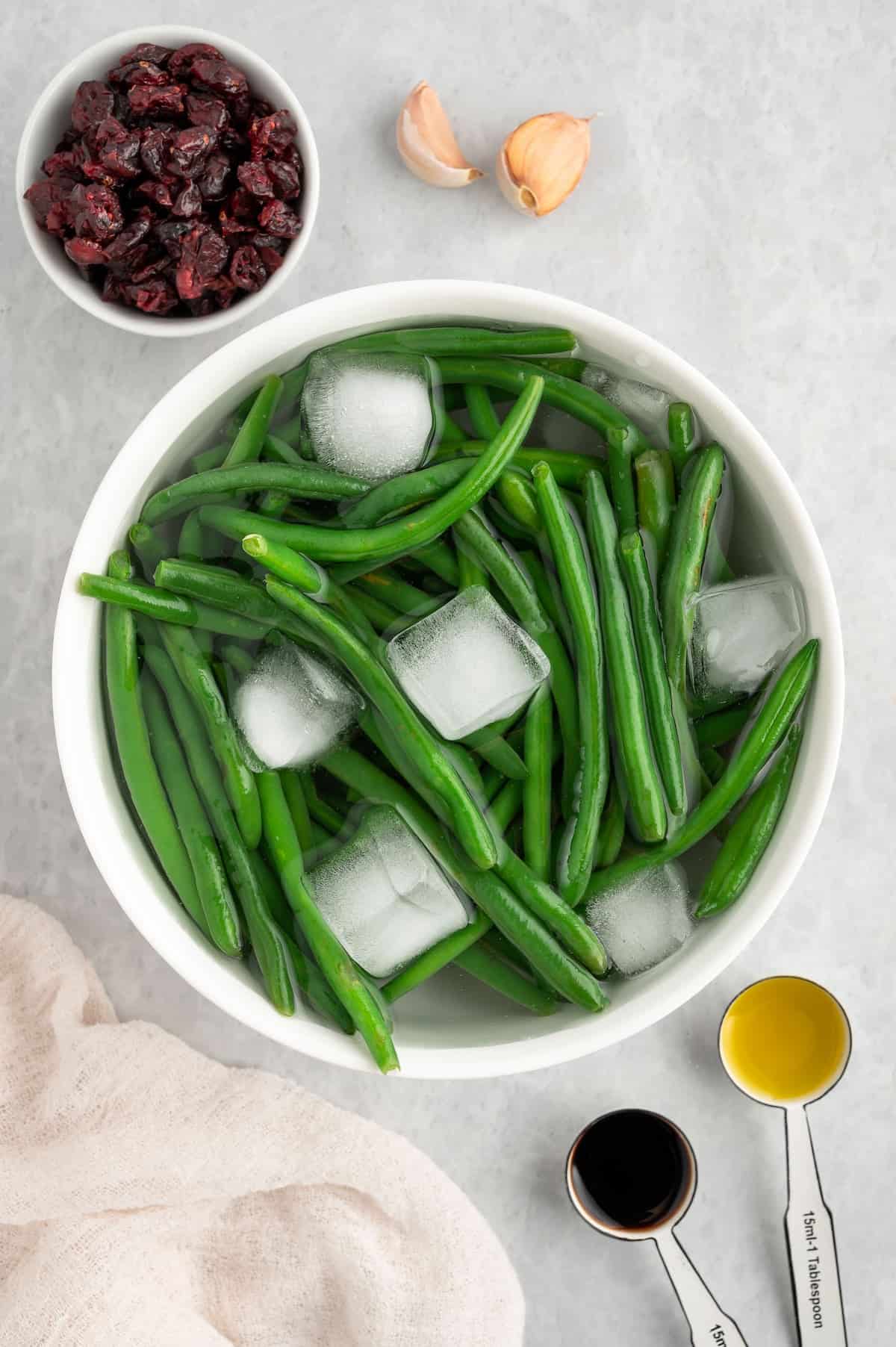 A bowl of green beans in ice water.