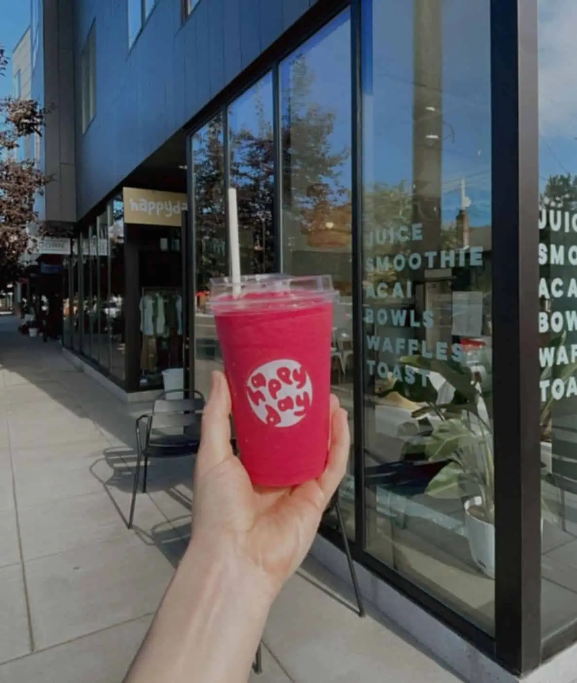 A hand holding up a juice from Happy Day Juice in Portland.