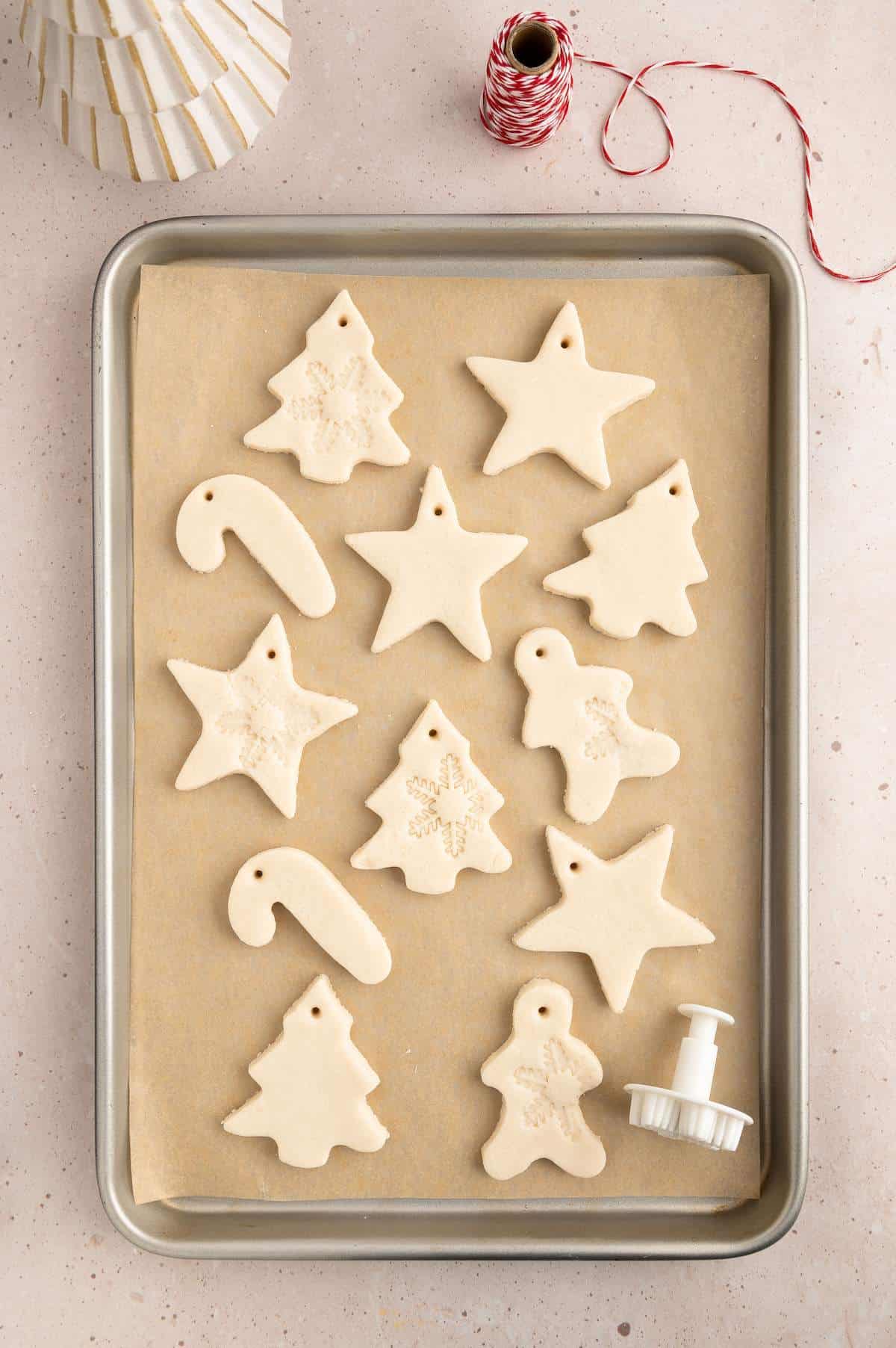 Holiday shaped salt cough ornaments on baking sheet ready to bake.