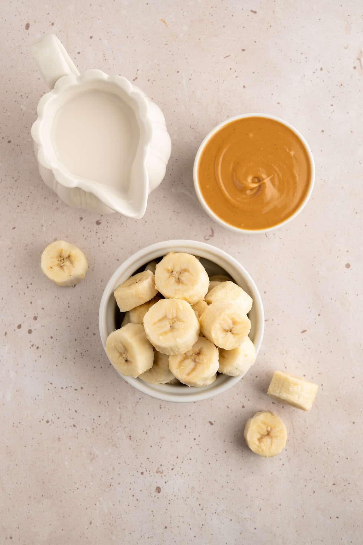 Overhead of ingredients for vegan peanut butter banana milkshake including soy milk, peanut butter and banana.