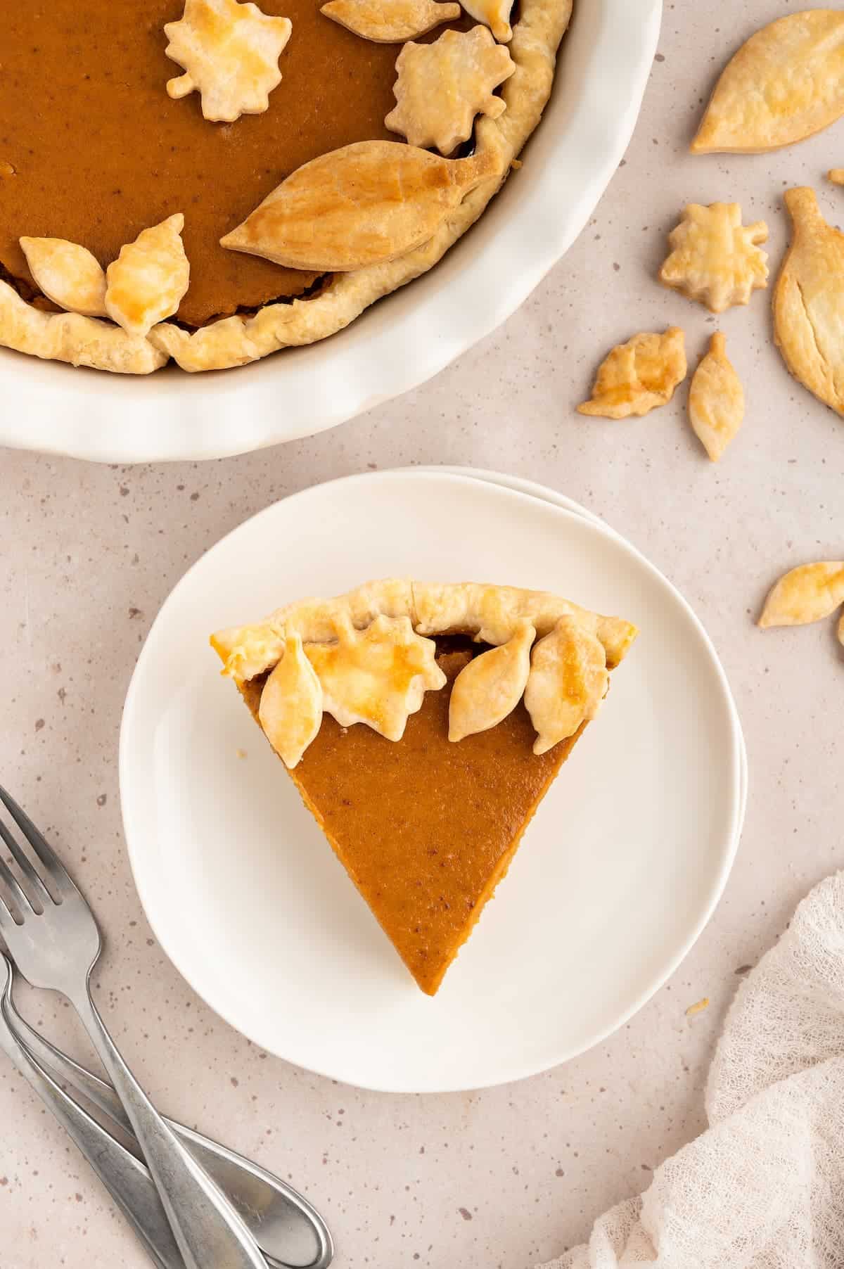 Overhead view of a slice of vegan sweet potato pie on a plate and decorated with pastry leaves.