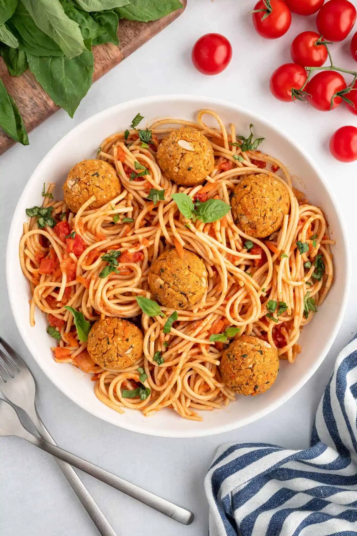 A bowl of pasta with sauce, veggie meatballs, and basil garnish.