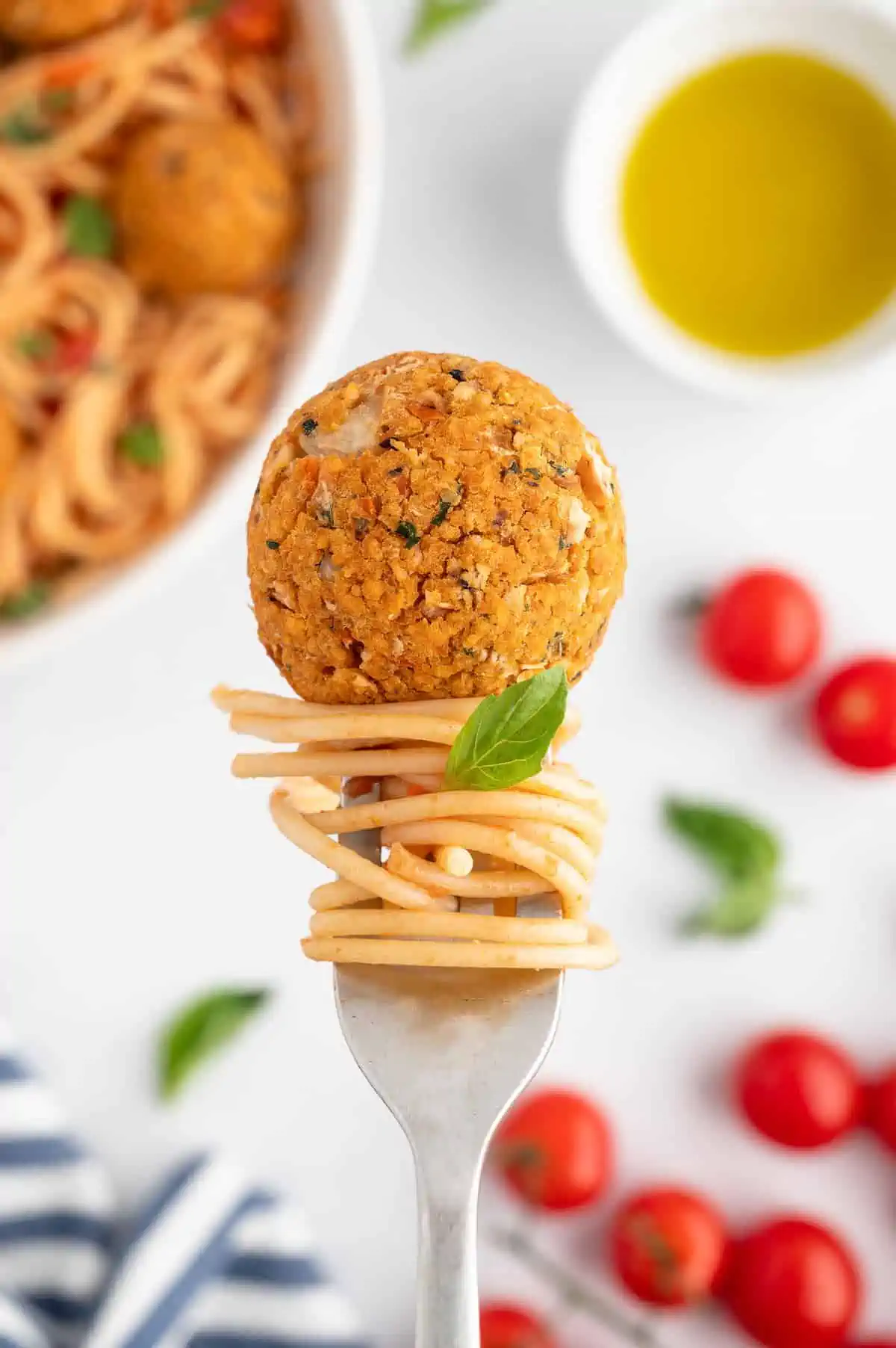 Pasta twisted on a fork with a veggie meatball on top.