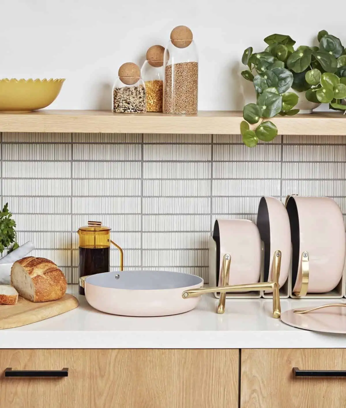 Caraway cookware set in light pink with pots and pans set up on a countertop.