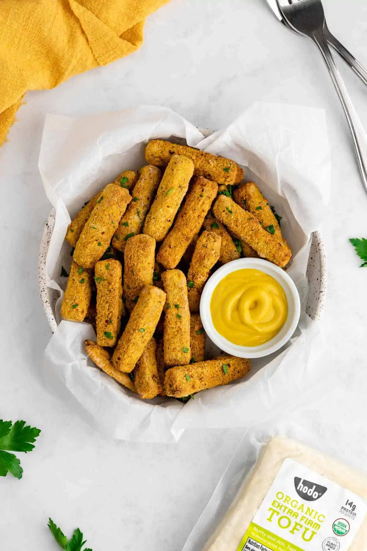 Crispy tofu fries in a bowl served with mustard and garnished with parsley. 
