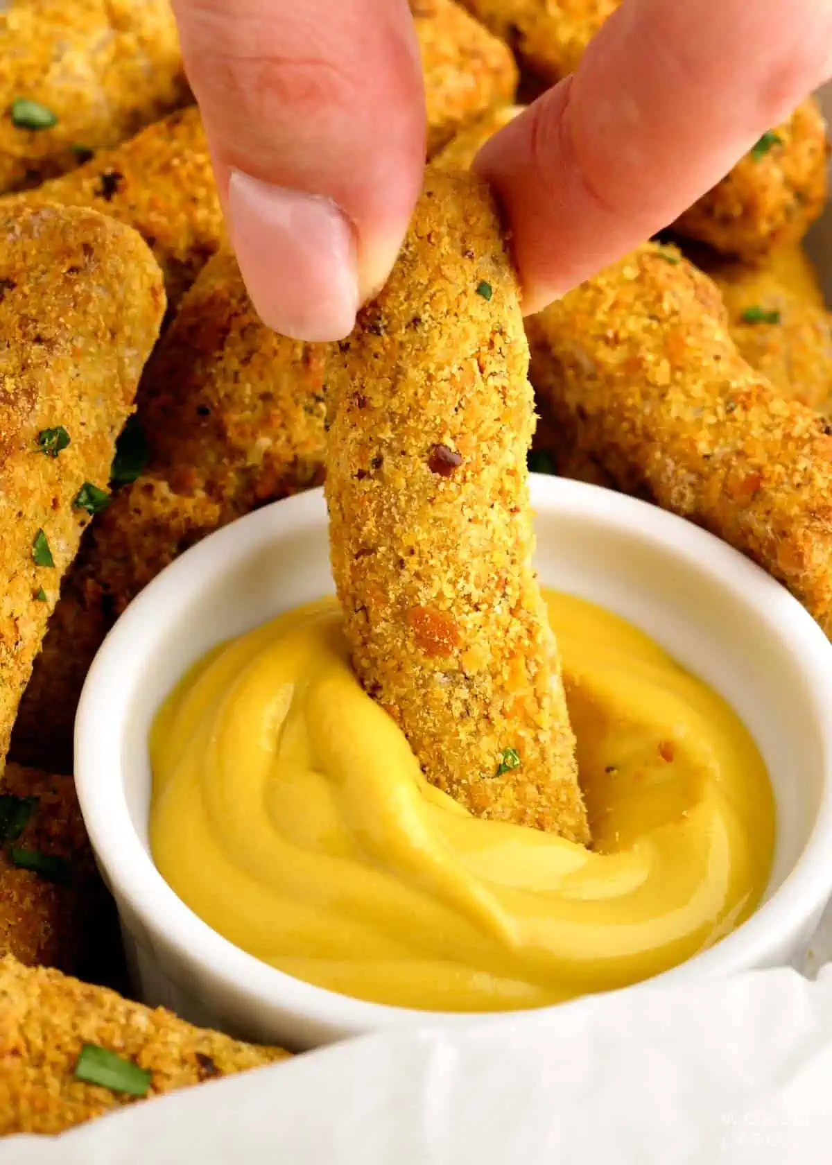 Dipping air fried tofu into yellow mustard. 