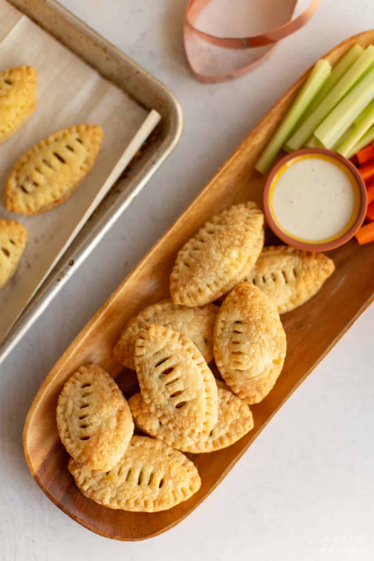 Baked football shaped puff pastry appetizer on a plate with celery and carrots. 