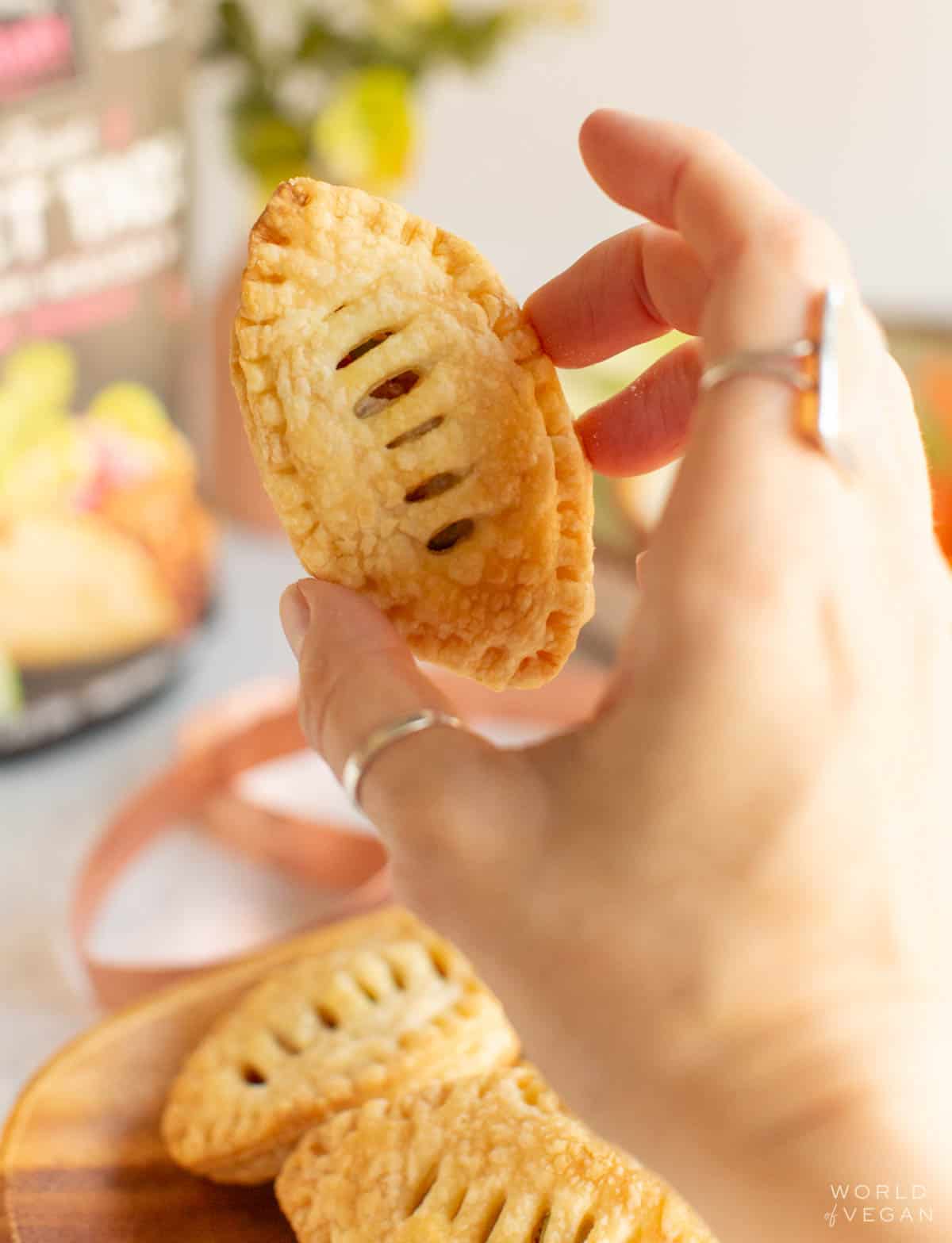 Holding up a savory baked puff pastry shaped like a football. 