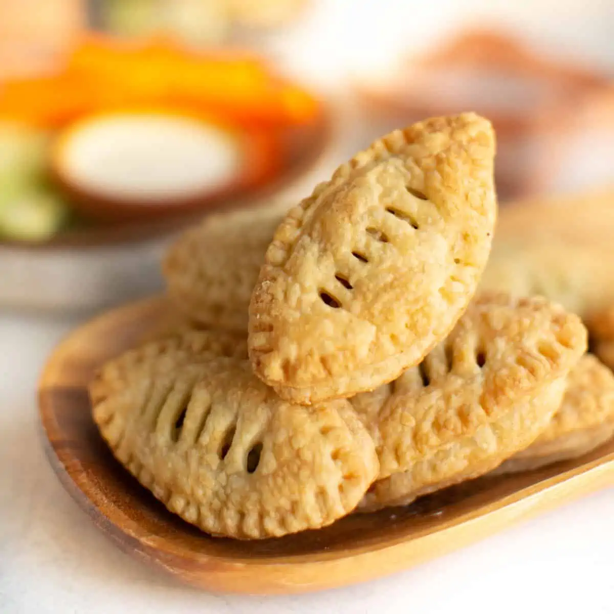 Adorable football puff pastry appetizer for SuperBowl or game days on a wood plate.