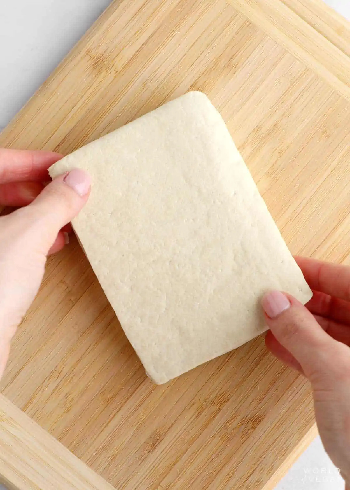 Block of extra firm tofu on a cutting board.