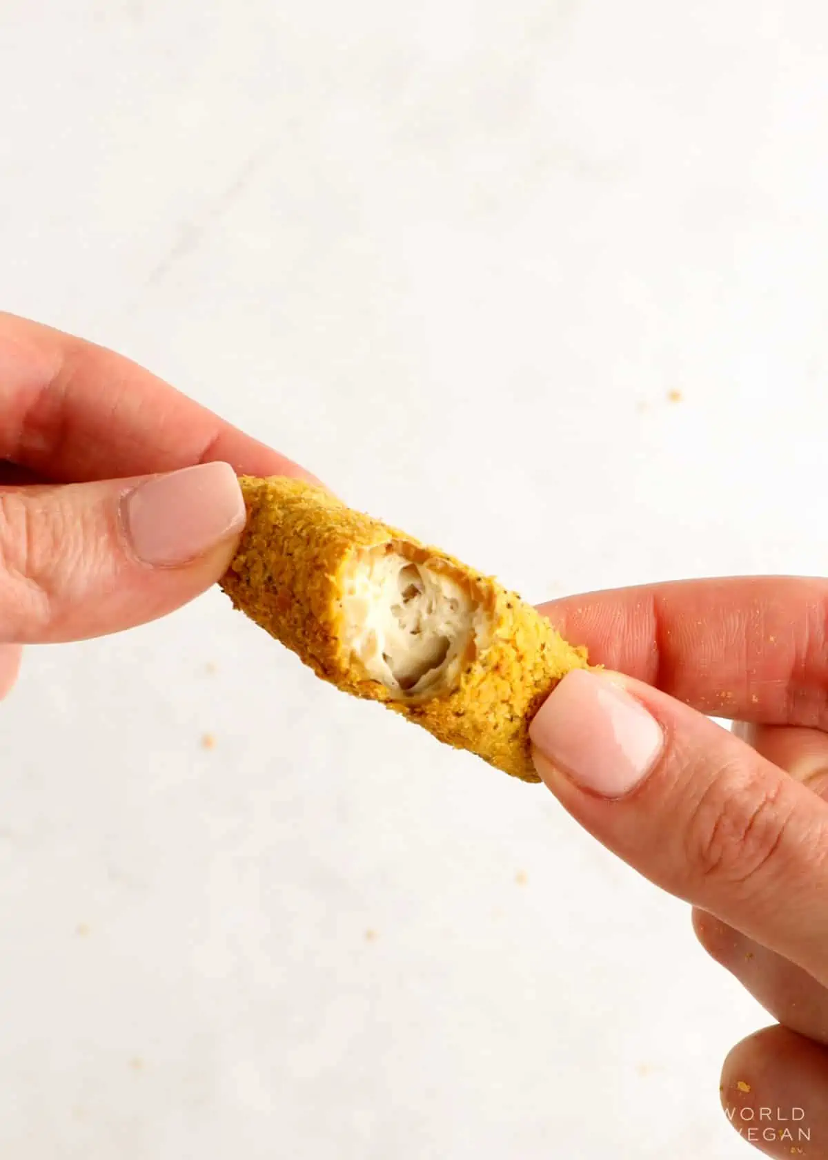Breaking apart a tofu fry  to show the crispy exterior and soft center. 