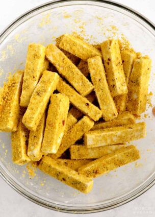 Tofu fries in mixing bowl with nutritional yeast added.