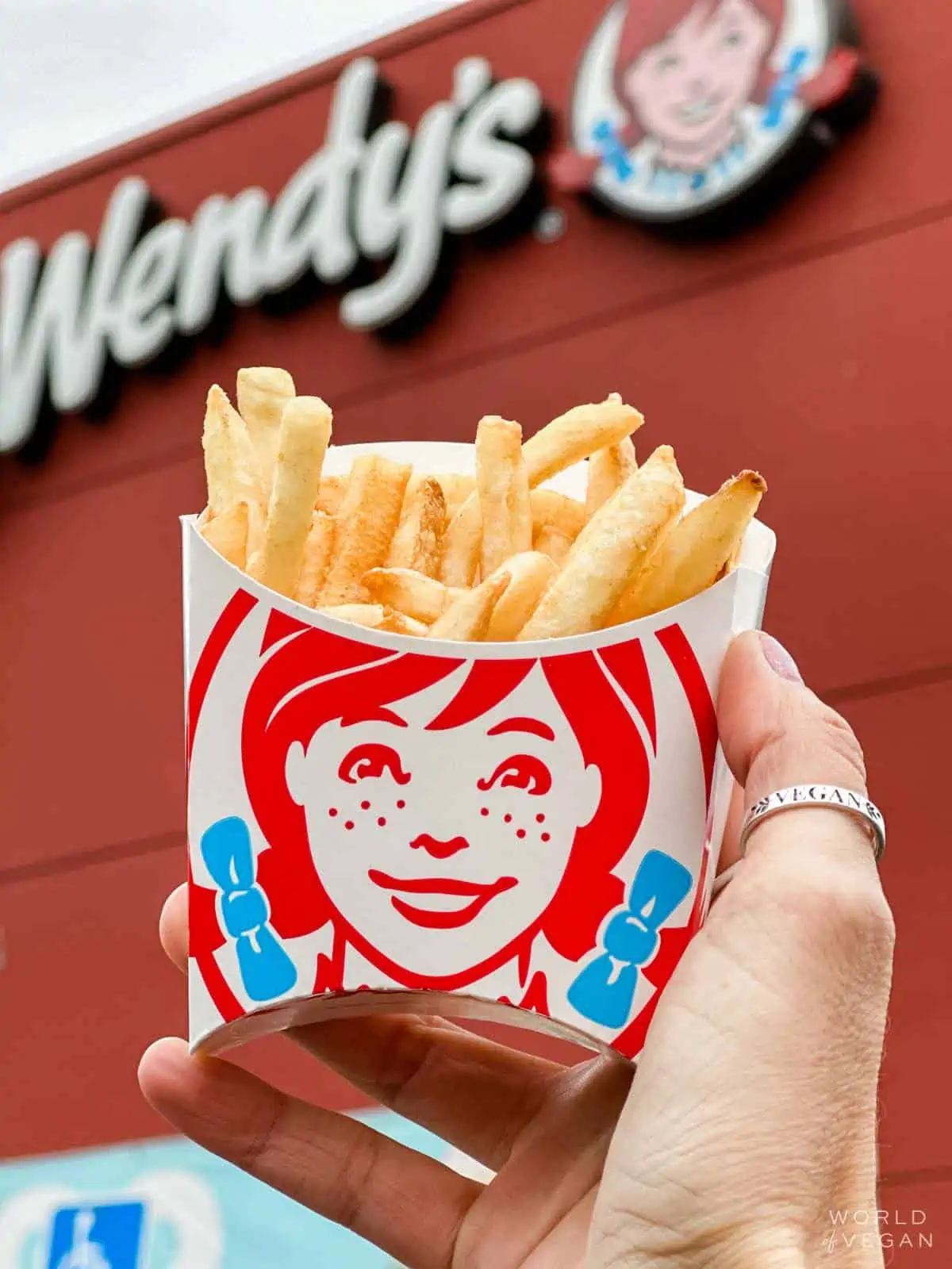 Vegan woman holding out a small order of Wendy's french fries.