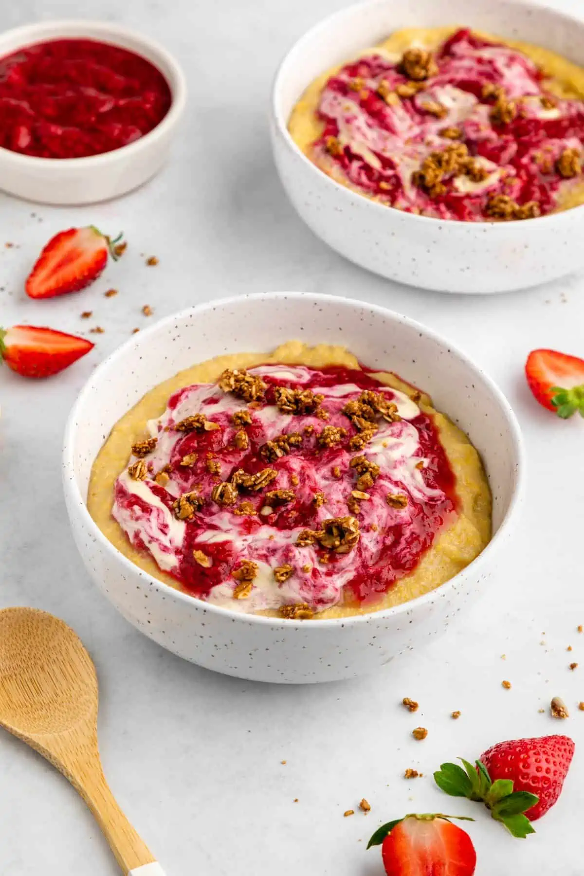 Vegan grits in a bowl topped with a berry compote, cashew cream and granola.