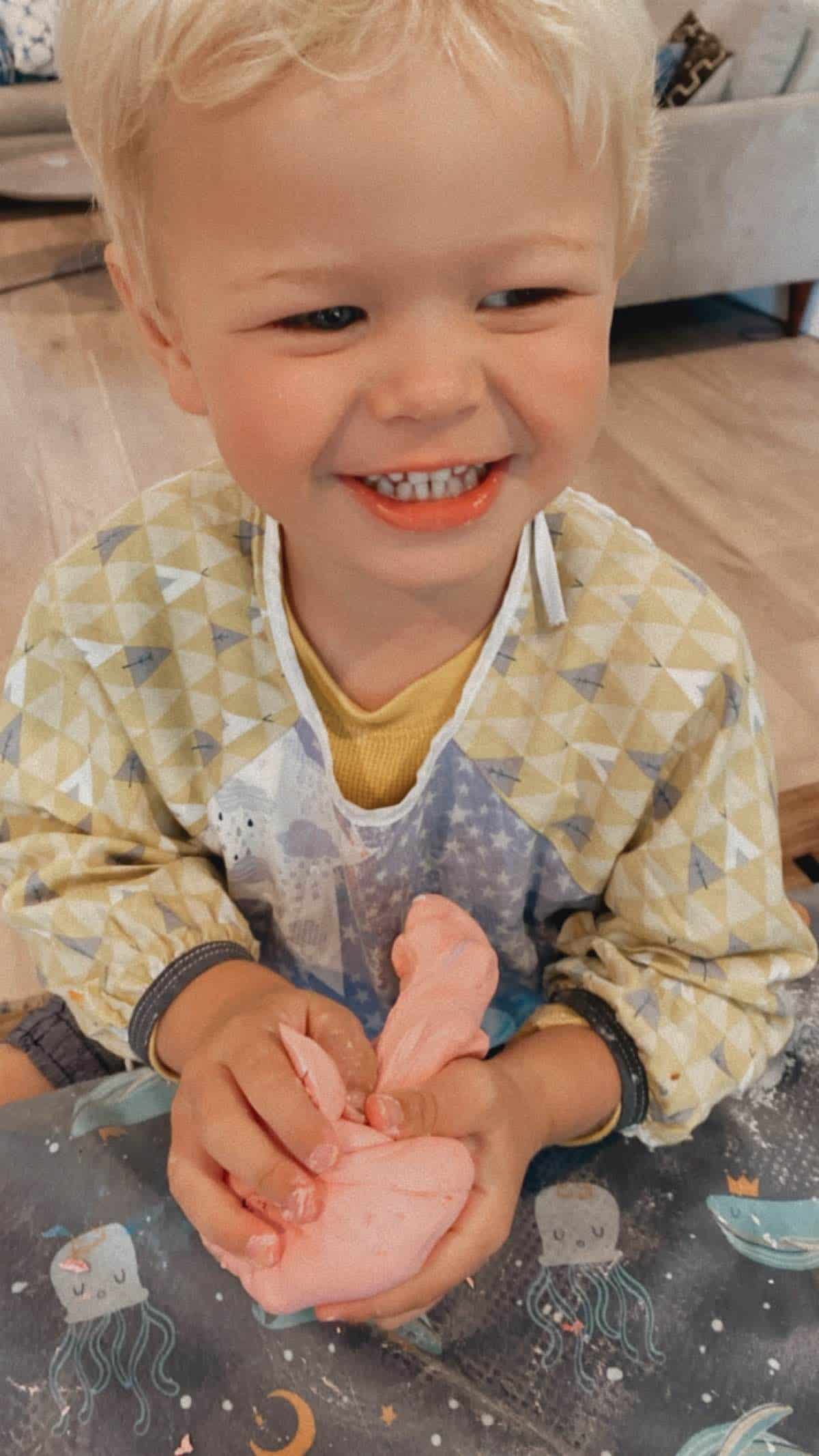 Vegan kid Graham Miller holding a pink ball of homemade could dough. 