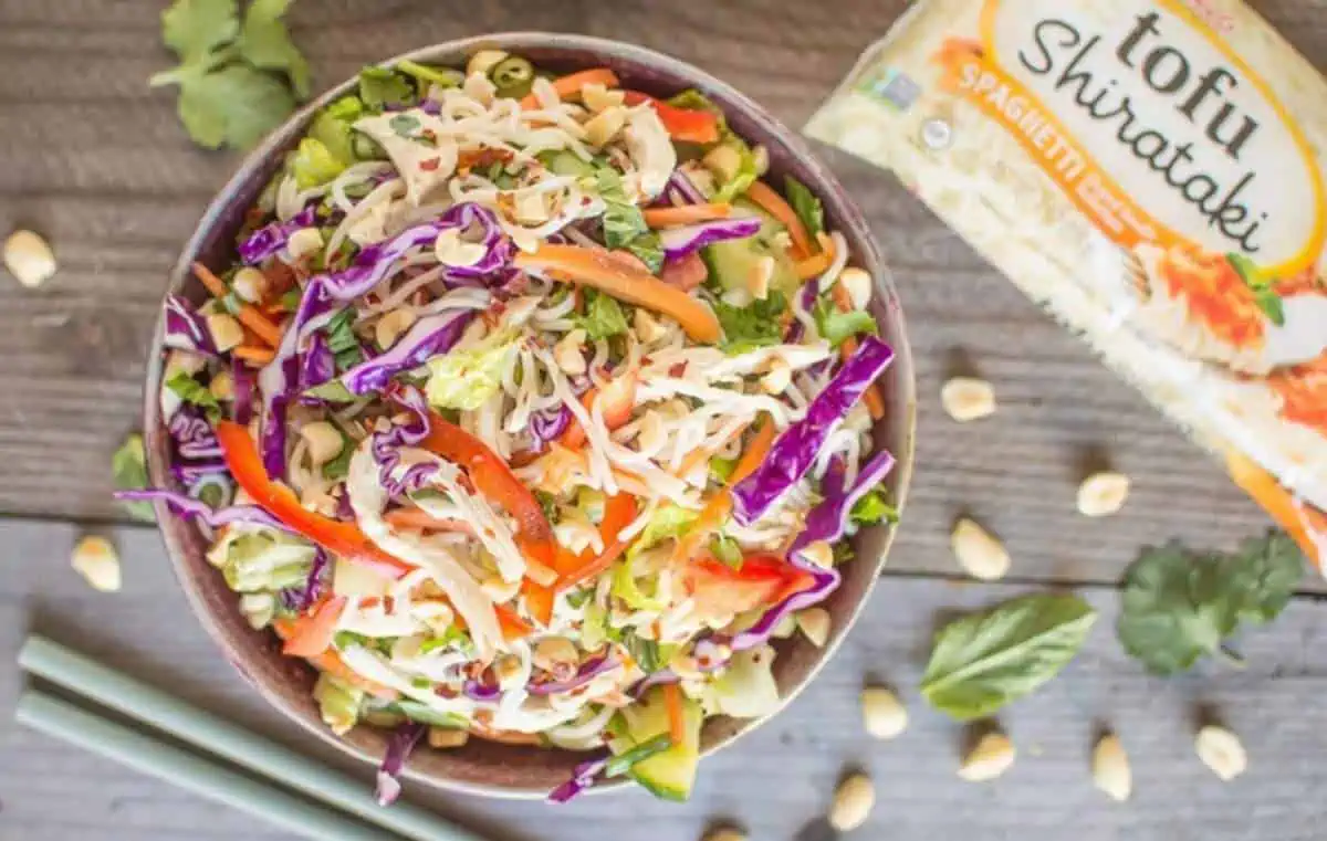 A bowl of peanut noodle salad using shirataki noodles from House Foods with the packaging beside it.