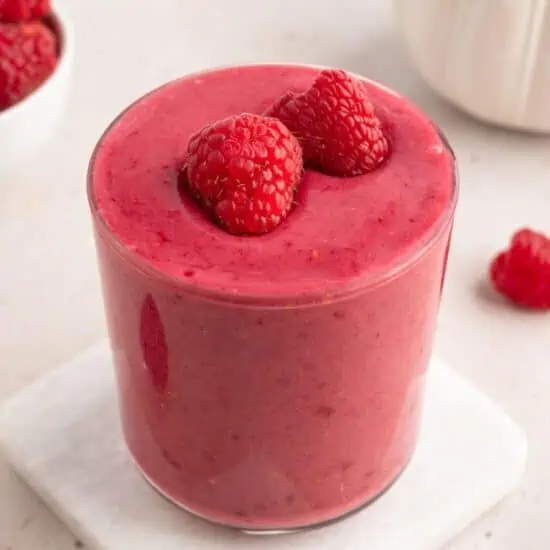 A raspberry smoothie with raspberries on top.