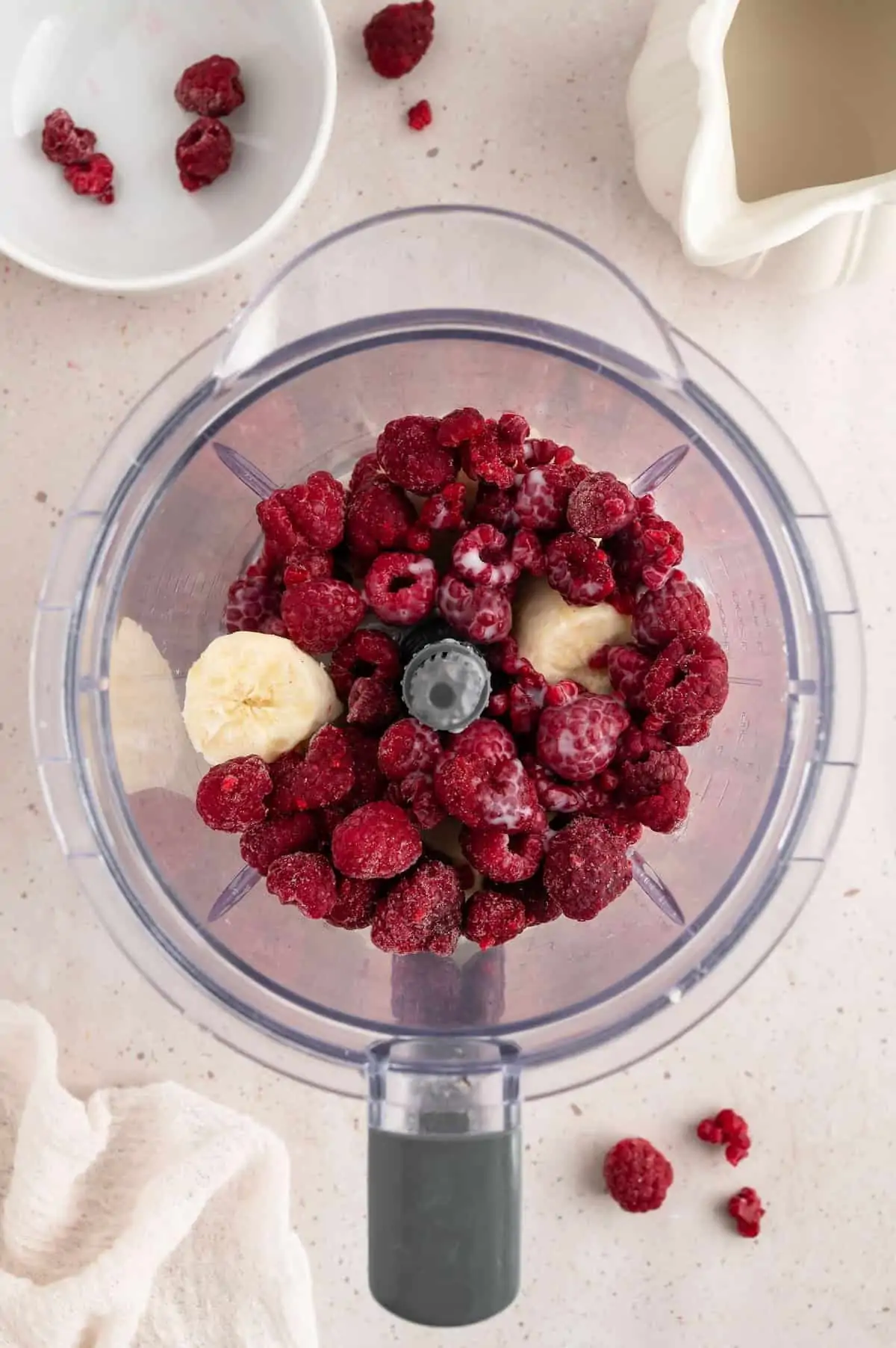 Raspberries and banana slices in a blender.