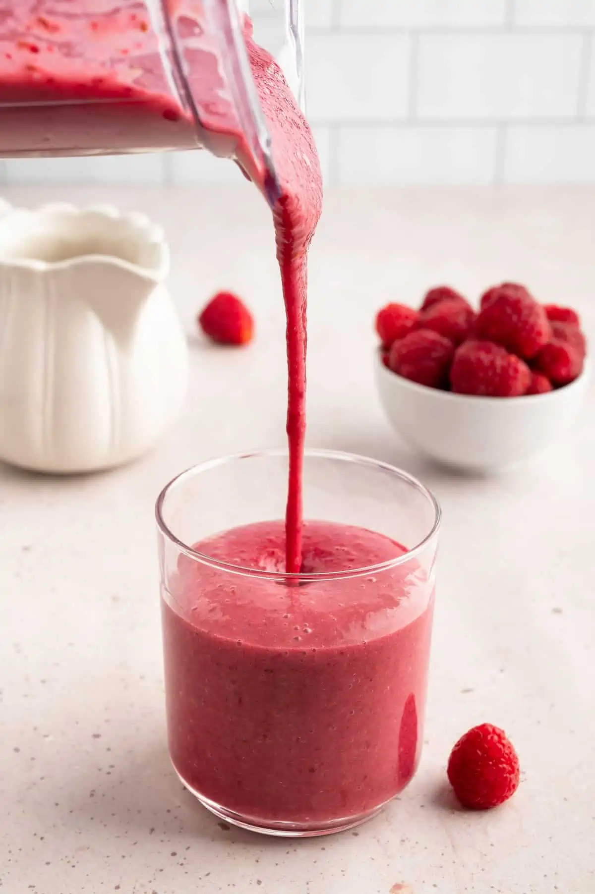 A raspberry smoothie being poured into a glass.