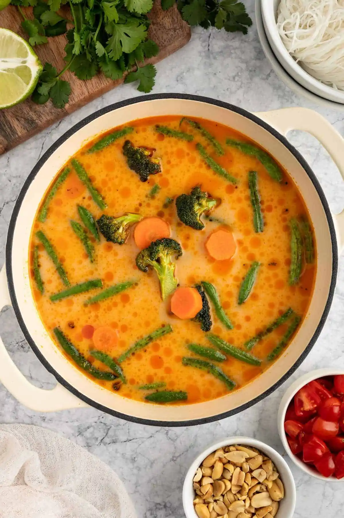 A pot with broth, vegetables, and coconut milk simmering.