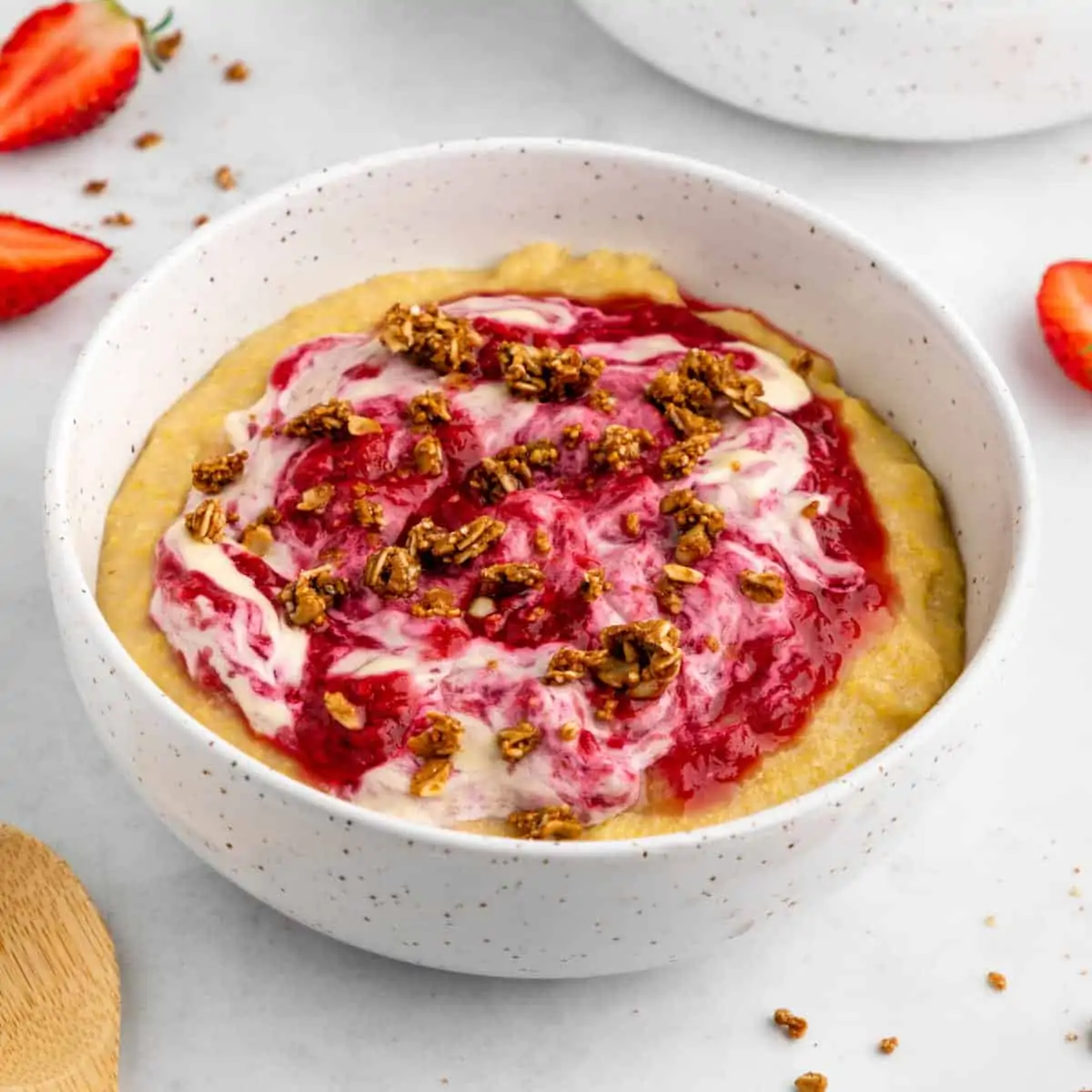 Vegan grits in a bowl topped with a berry compote, cashew cream and granola.