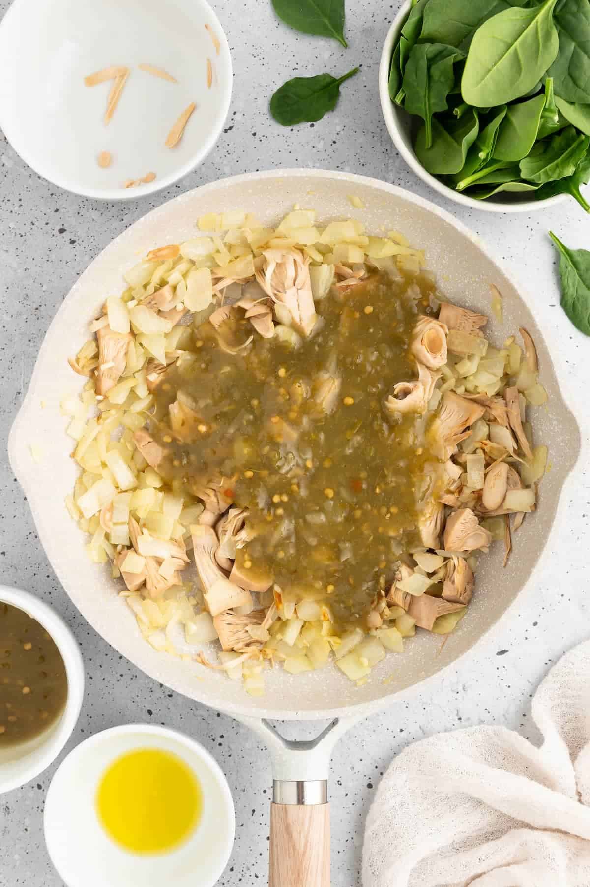 Onions, jackfruit and salsa verde simmering in a pan.