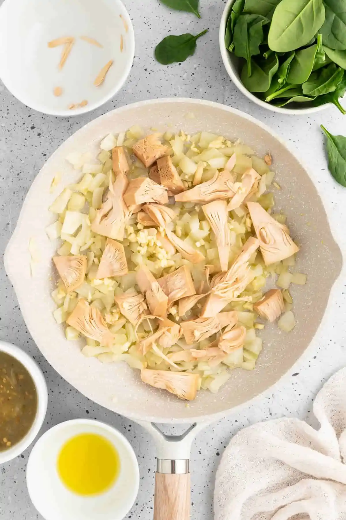 Onions and jackfruit simmering in a pan.