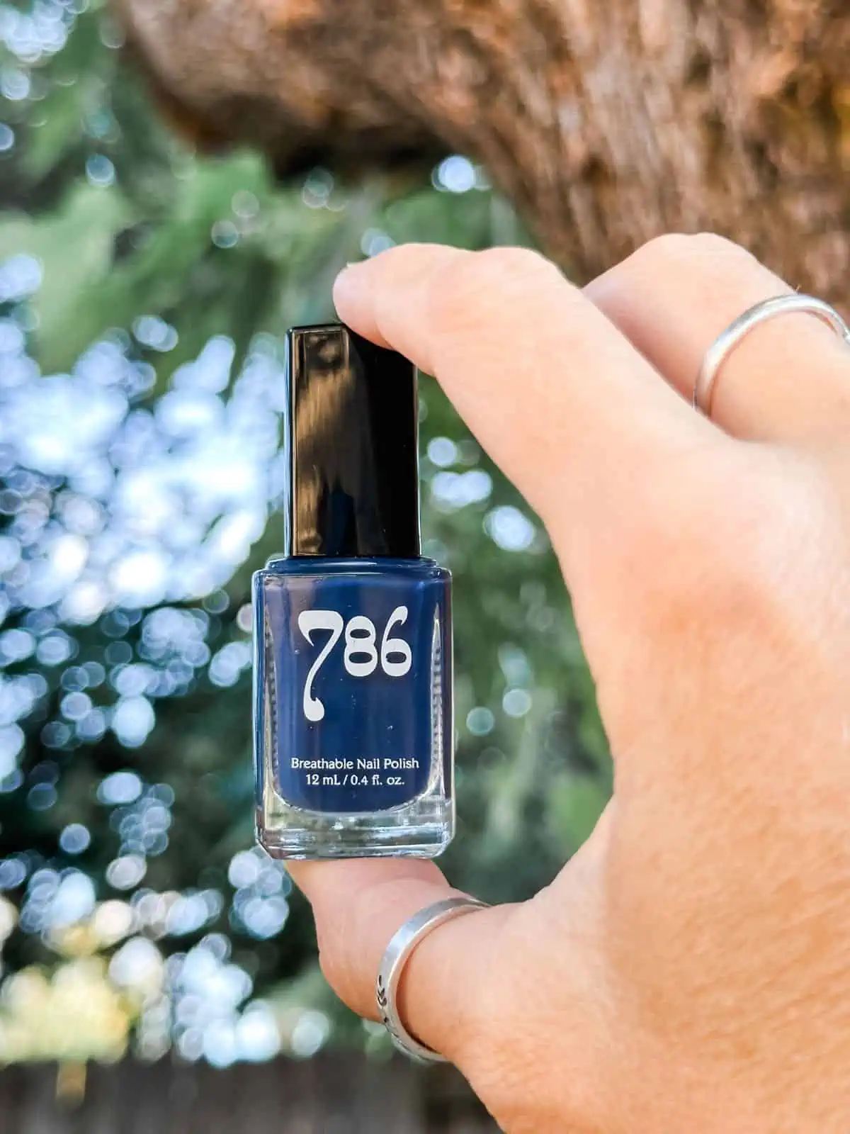 Vegan woman holding up blue cruelty-free nail polish from the brand 786 Cosmetics. 