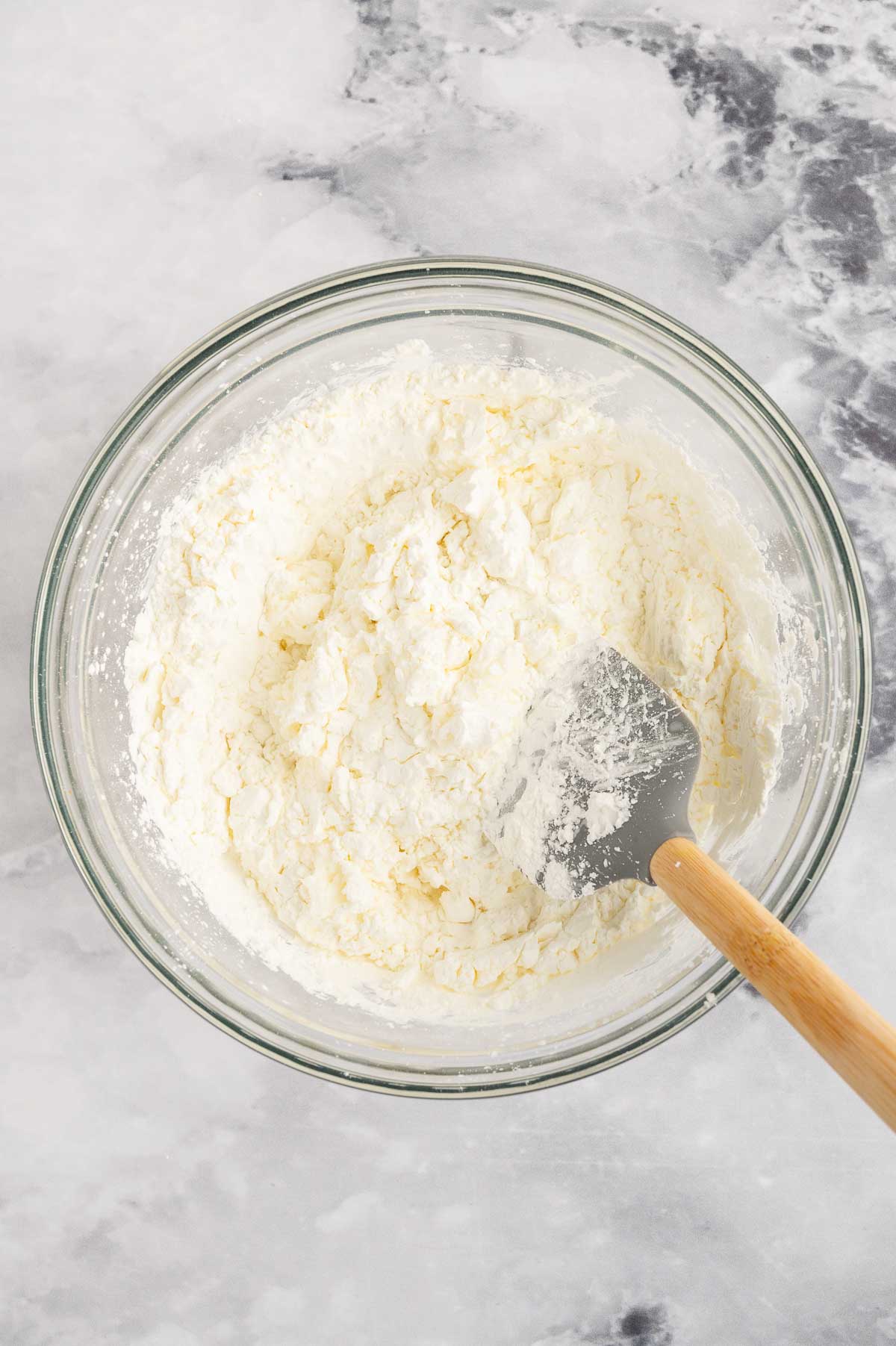 Cloud dough ingredients in a bowl with a spatula.