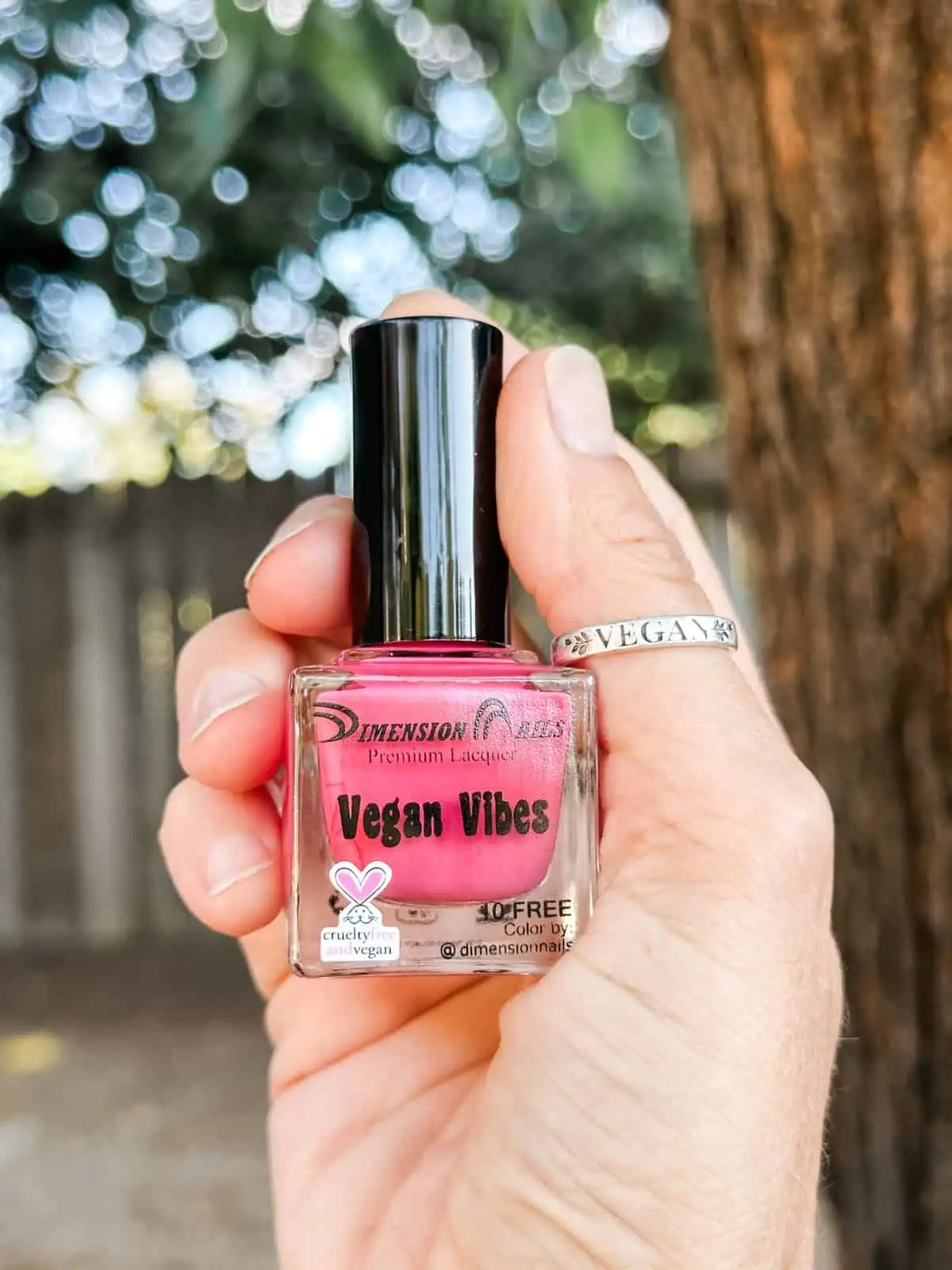 Bottle of pink vegan nail polish from Dimension Nails with the cruelty-free bunny logo. 