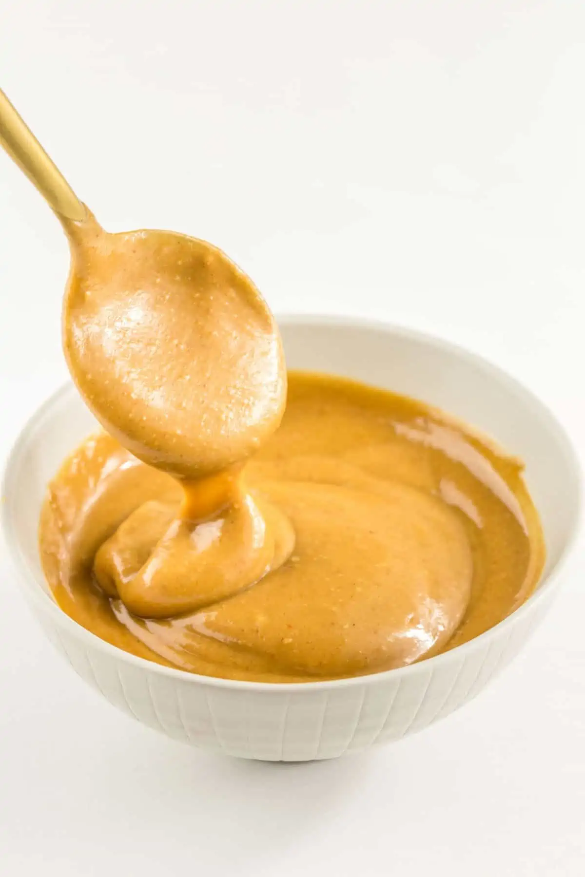 Peanut sauce dressing in a small bowl with a spoon—perfect for salads or grain bowls.
