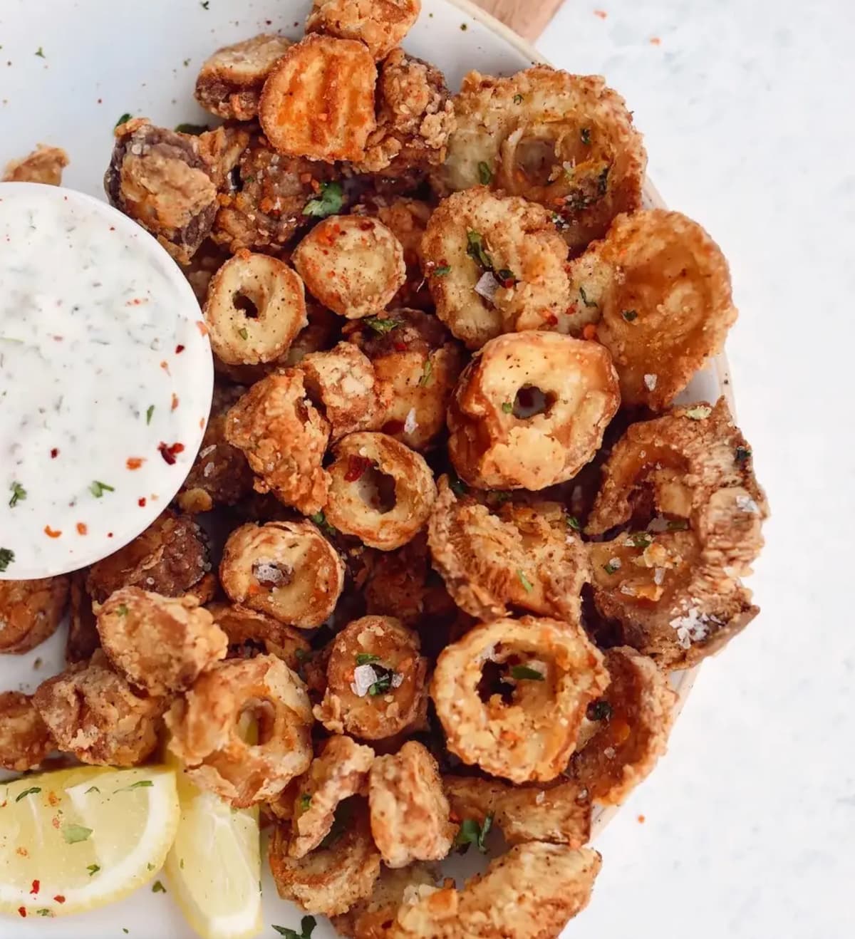 A platter of fried vegan calamari with a creamy dipping sauce.