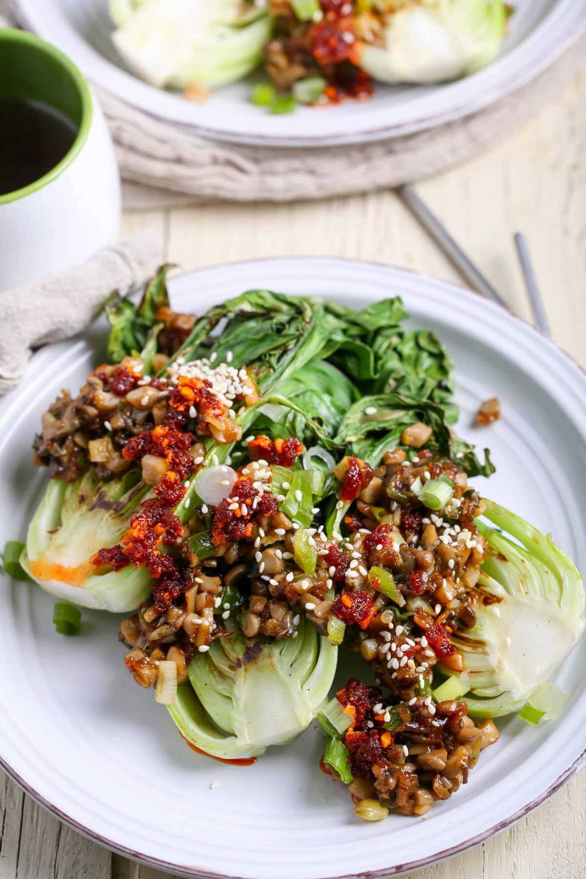 A plate of grilled bok choy topped with oyster mushrooms.