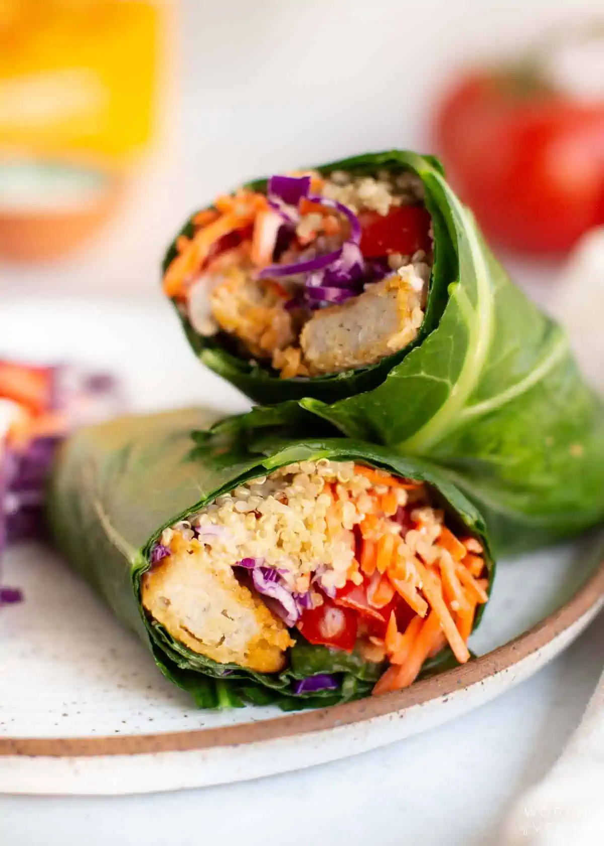 Two halves of a collard green wrap stacked on a plate.