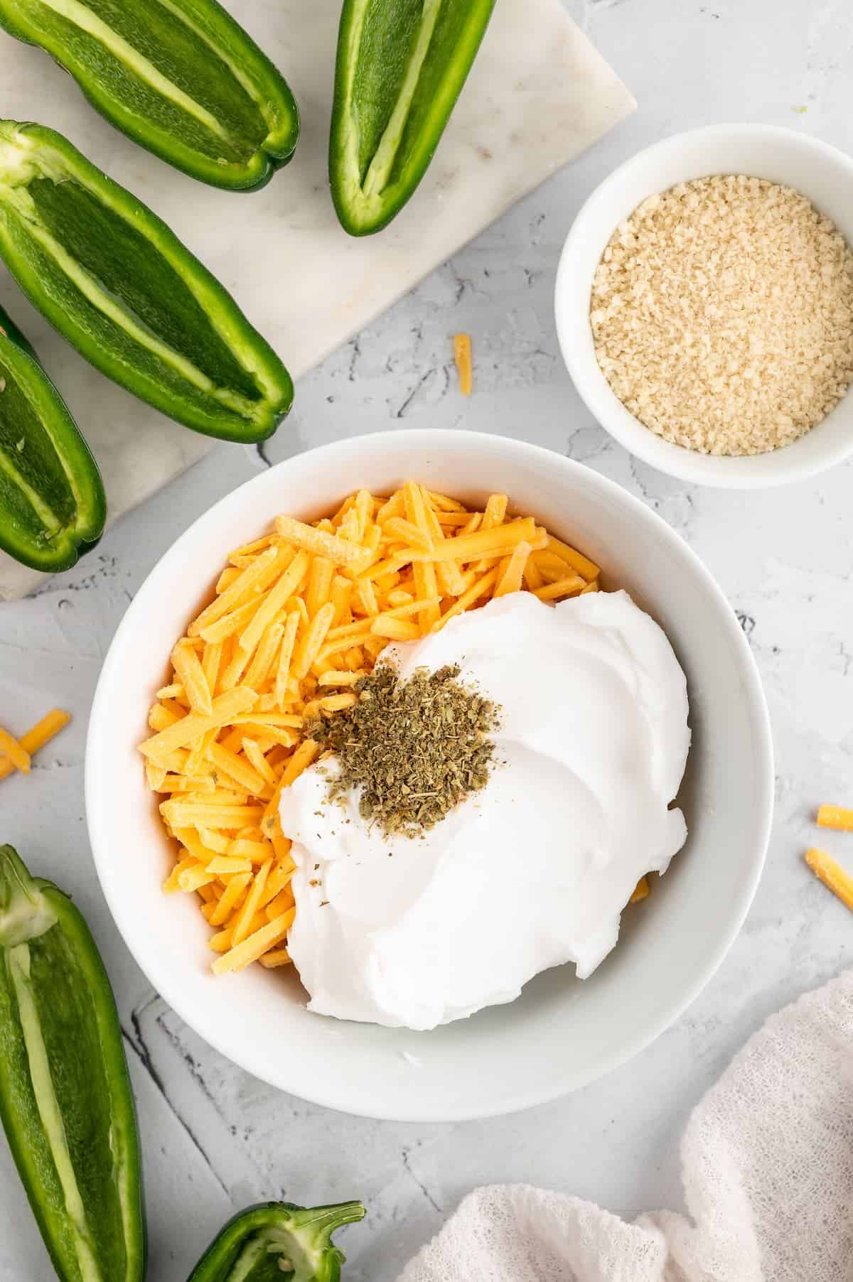 A white bowl with vegan cheese, vegan cream cheese, and oregano.