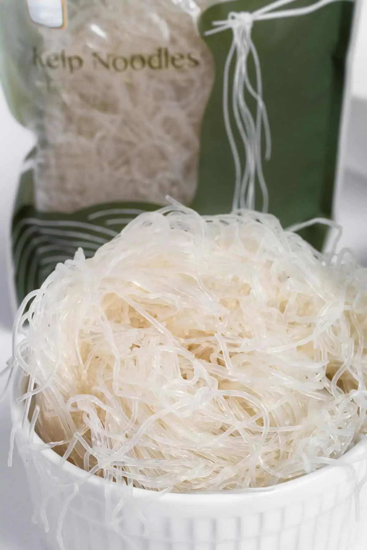 Bowl of prepare kelp noodles with the package behind it.