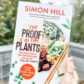 Vegan woman holding out Simon Hill's book The Proof is in the Plants.
