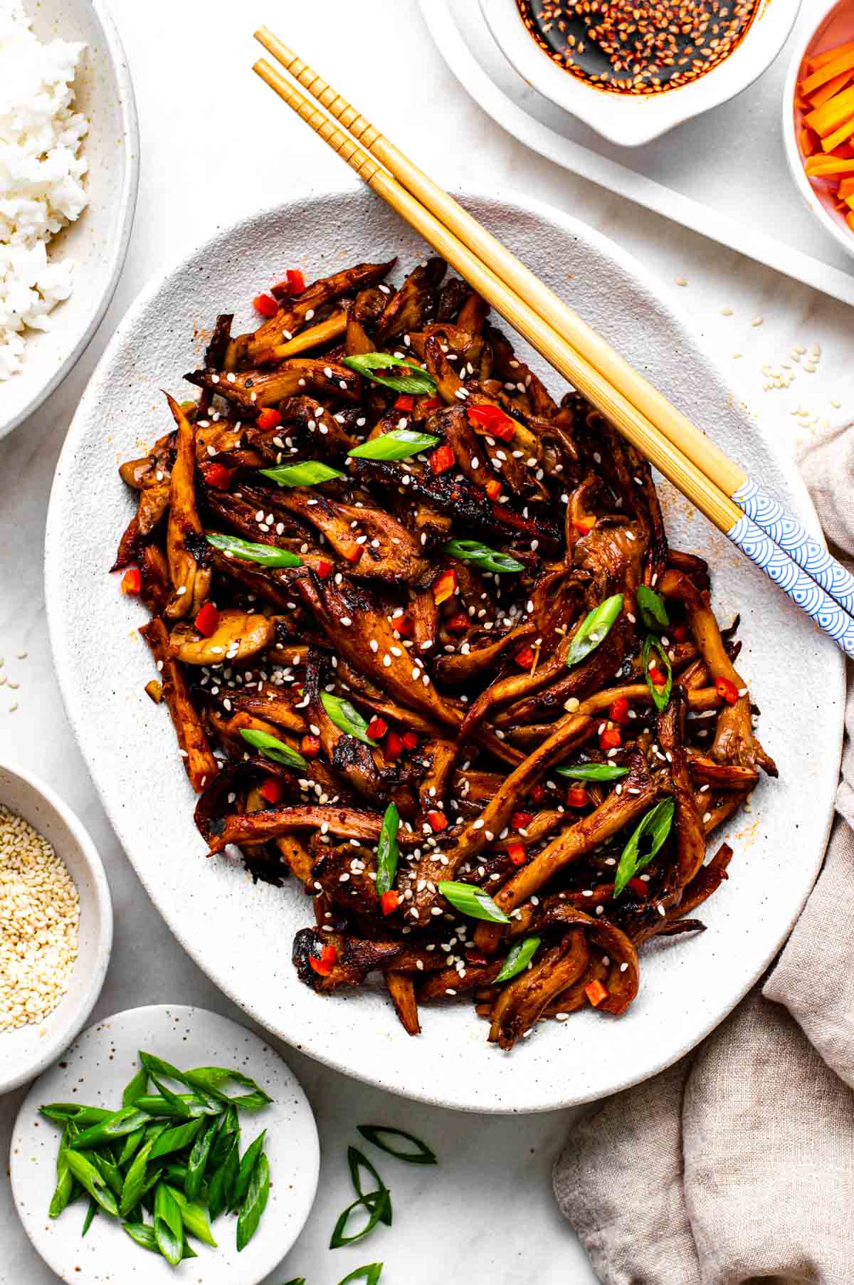 A platter of vegan bulgogi made with oyster mushrooms and garnished with sliced green onions and sesame seeds.