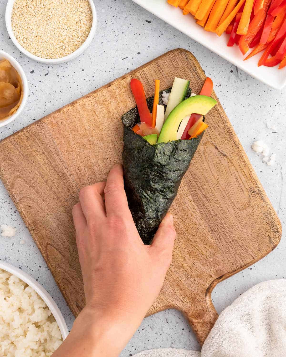 Sealing the finished temaki sushi hand roll.