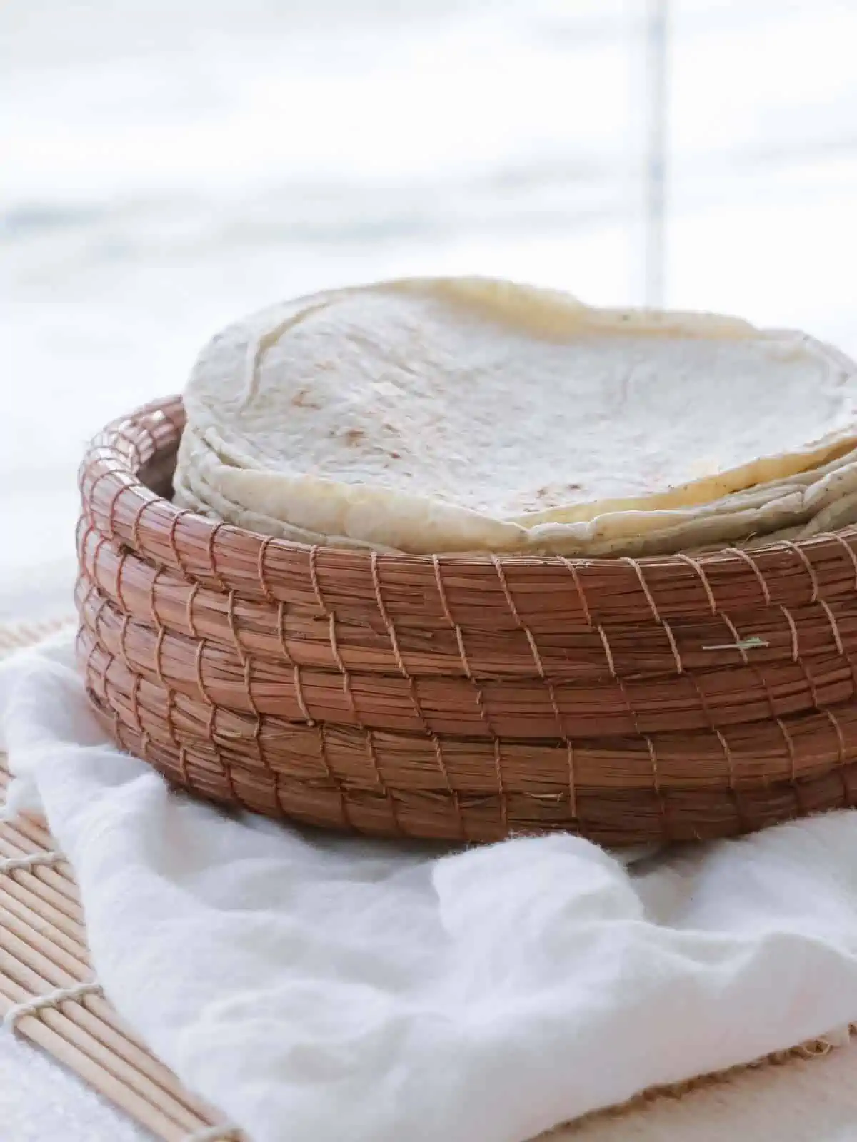 Vegan flour tortillas stacked in a woven basket.