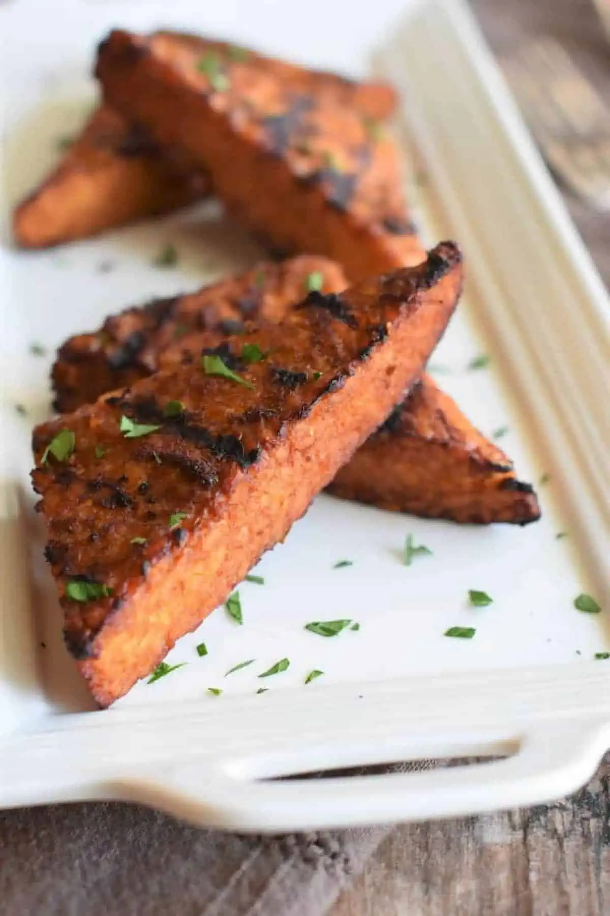 Tofu steak on a plate, sprinkled with chopped fresh herbs.