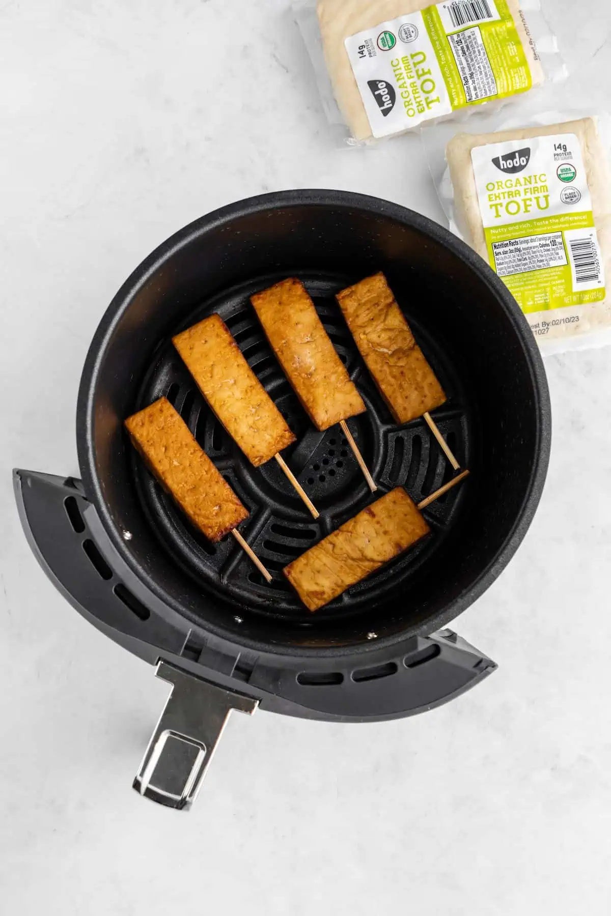 Tofu satay in an air fryer basket after its been cooked can become golden brown.