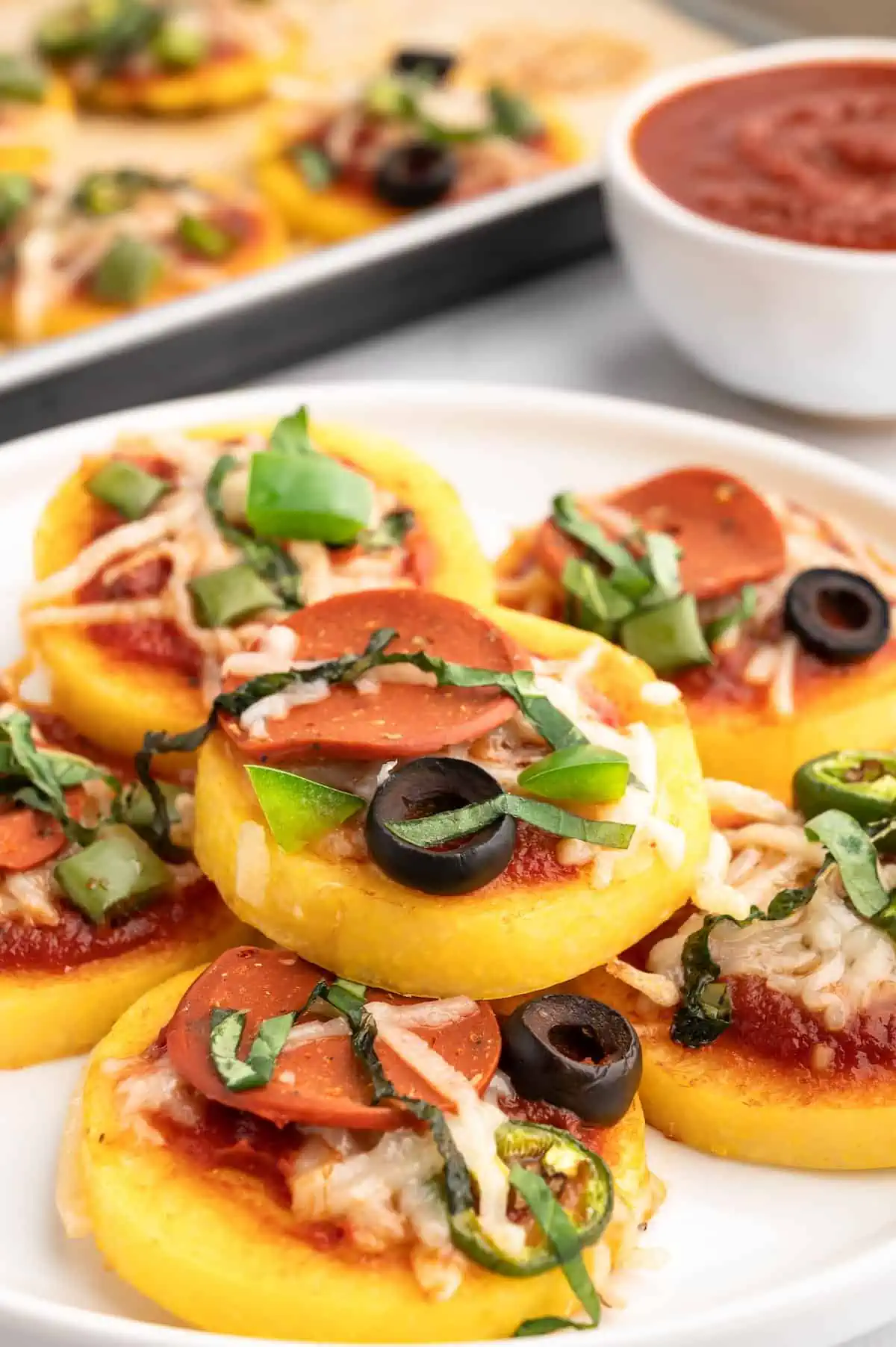 A stack of polenta pizza bites on a plate.