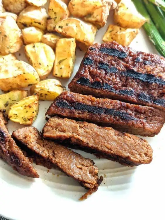 Seitan vegan steak cut into slices, on a plate with potatoes.