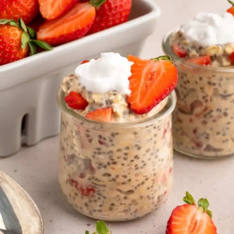 A close-up shot of strawberries and cream overnight oats in a glass jar.