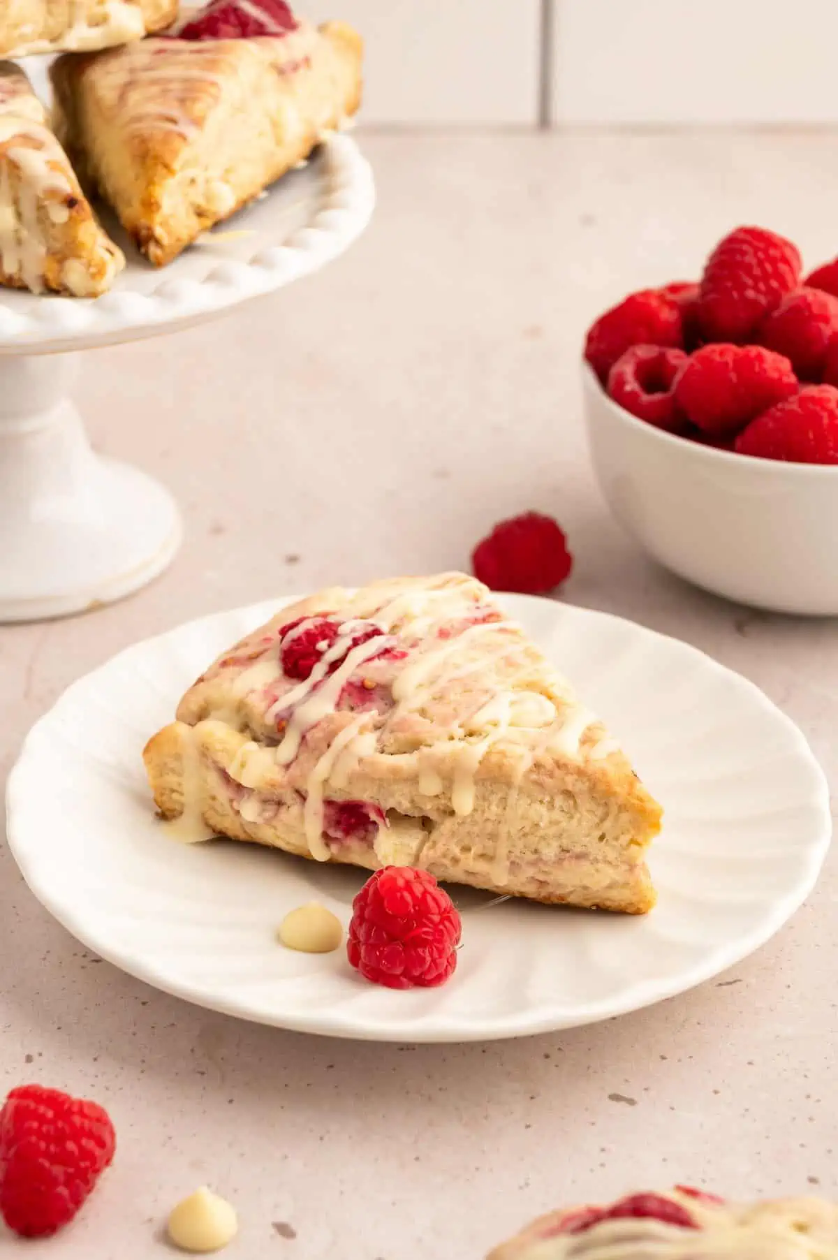 A vegan scone on a plate with raspberries.